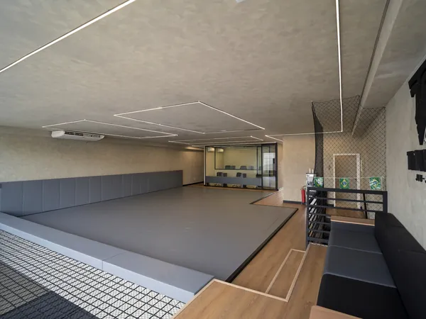 Tatame do andar superior da Trivium Jiu-Jitsu, com sofá ao lado
