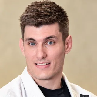 Carlos Busso, sócio-fundador da Trivium Jiu-Jitsu, de kimono e faixa preta no tatame